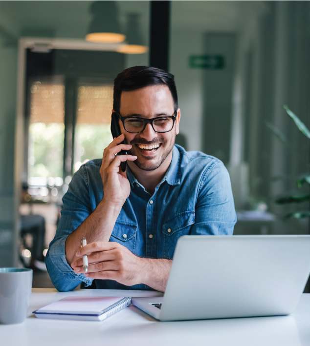 Man talking on phone in office environment with laptop